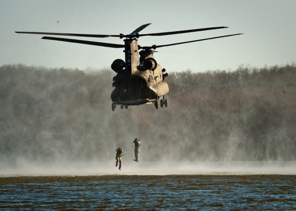 Heavy-lift helicopter hovering as personnel fast-rope to the ground